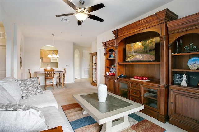 carpeted living room with built in shelves and ceiling fan with notable chandelier