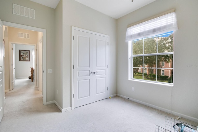 unfurnished bedroom with light colored carpet and a closet