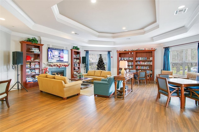 living room with hardwood / wood-style flooring, a raised ceiling, a wealth of natural light, and crown molding