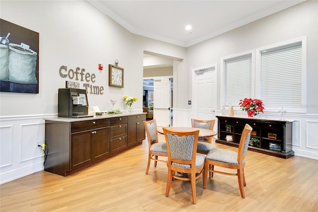 dining space featuring ornamental molding and light hardwood / wood-style flooring