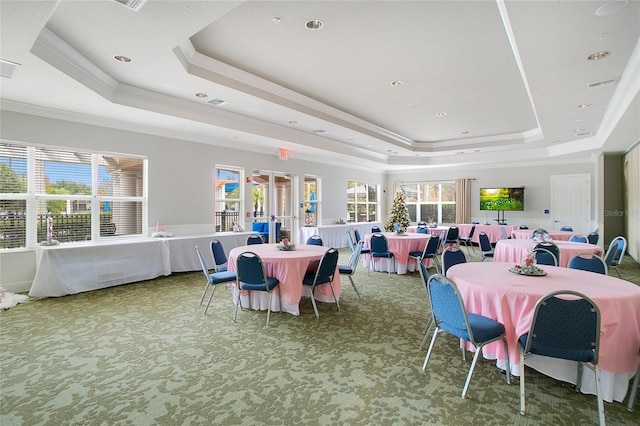 carpeted dining area with a tray ceiling and crown molding