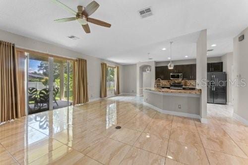 kitchen featuring refrigerator with ice dispenser, decorative backsplash, ceiling fan, and a healthy amount of sunlight