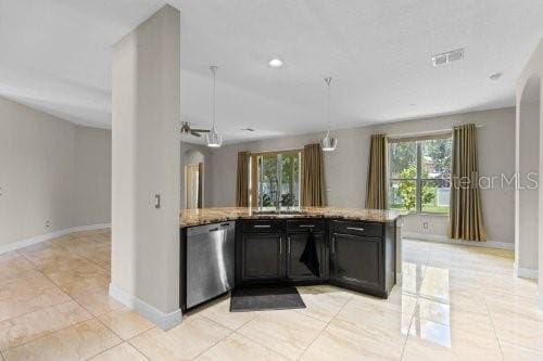 kitchen with light stone countertops, dishwasher, sink, pendant lighting, and light tile patterned floors