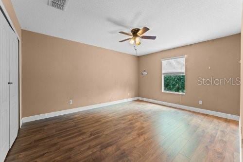 unfurnished bedroom with ceiling fan, dark hardwood / wood-style flooring, a textured ceiling, and a closet