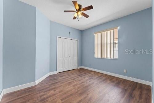 unfurnished bedroom with dark hardwood / wood-style flooring, a closet, and ceiling fan