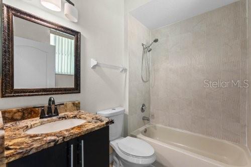 full bathroom featuring tiled shower / bath combo, toilet, and vanity