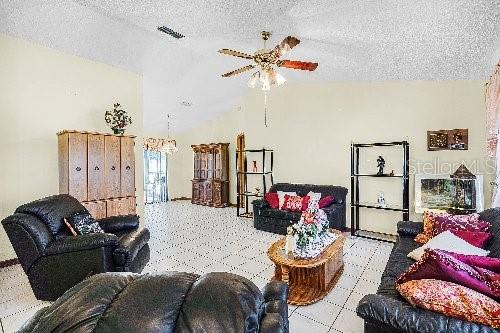 living room featuring ceiling fan and a textured ceiling