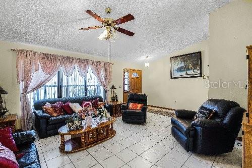 living room with ceiling fan and a textured ceiling