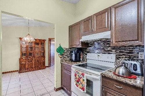 kitchen featuring dark brown cabinets, white range oven, and exhaust hood