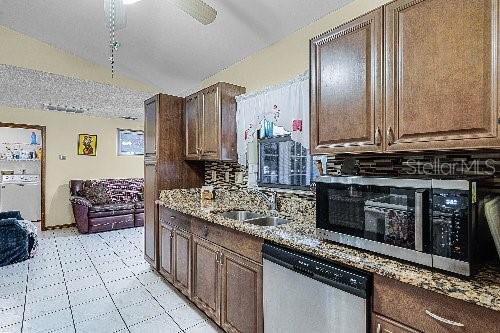 kitchen featuring ceiling fan, sink, light stone counters, vaulted ceiling, and appliances with stainless steel finishes