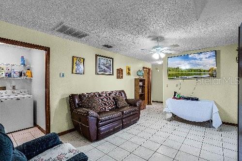 living room with ceiling fan, a textured ceiling, and washer / clothes dryer