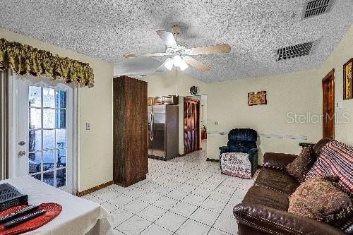 living room with ceiling fan and a textured ceiling