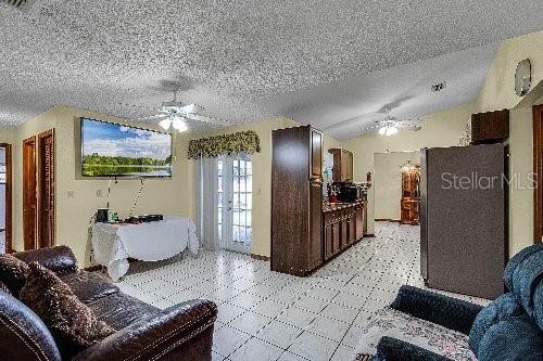 living room with ceiling fan, a textured ceiling, and vaulted ceiling