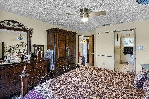 bedroom with ceiling fan and a textured ceiling