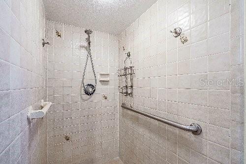 bathroom with a tile shower and a textured ceiling