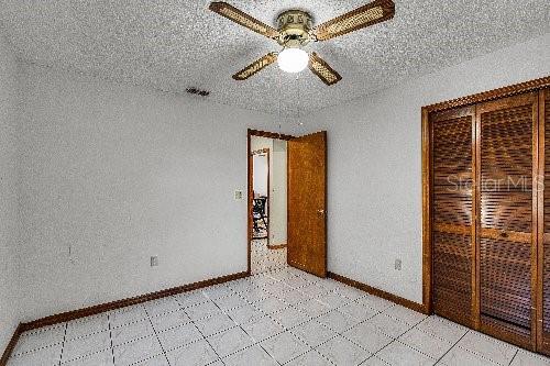 unfurnished bedroom featuring ceiling fan, a closet, and a textured ceiling