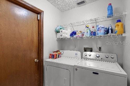 laundry area featuring washing machine and dryer and a textured ceiling