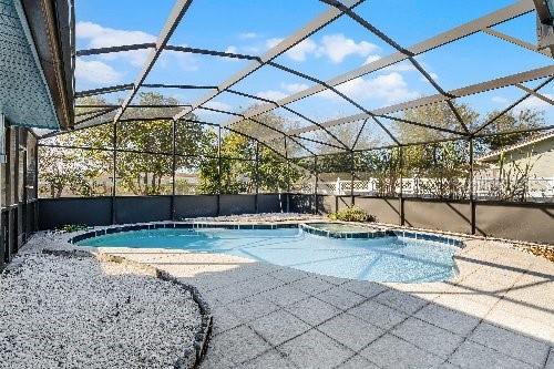 view of swimming pool with a patio area and glass enclosure