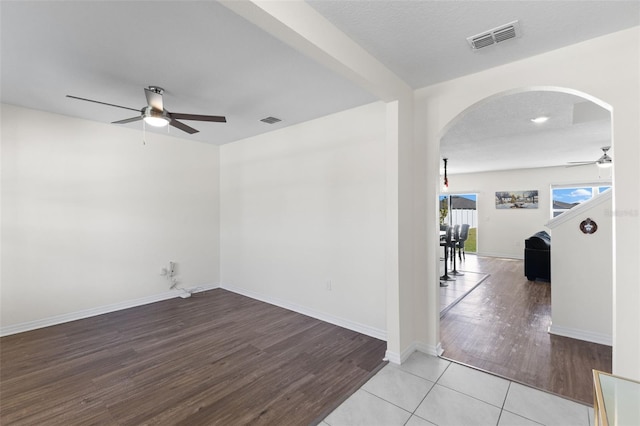 spare room featuring ceiling fan, beam ceiling, a textured ceiling, and light hardwood / wood-style flooring