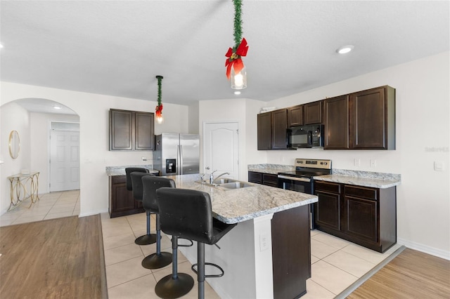 kitchen featuring sink, hanging light fixtures, light hardwood / wood-style flooring, a kitchen island with sink, and appliances with stainless steel finishes