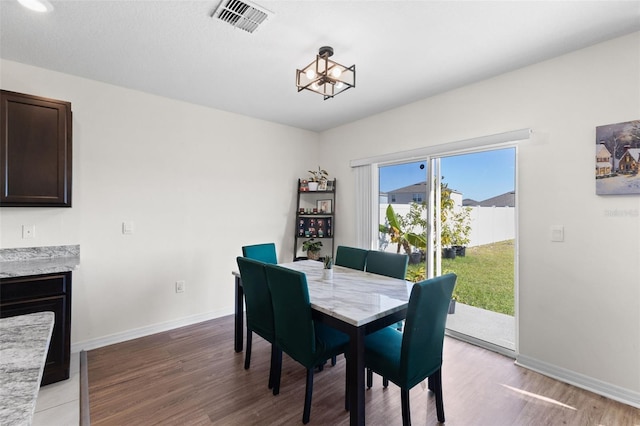 dining space with hardwood / wood-style floors and an inviting chandelier