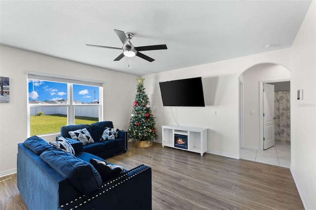 living room with hardwood / wood-style flooring, ceiling fan, and a textured ceiling