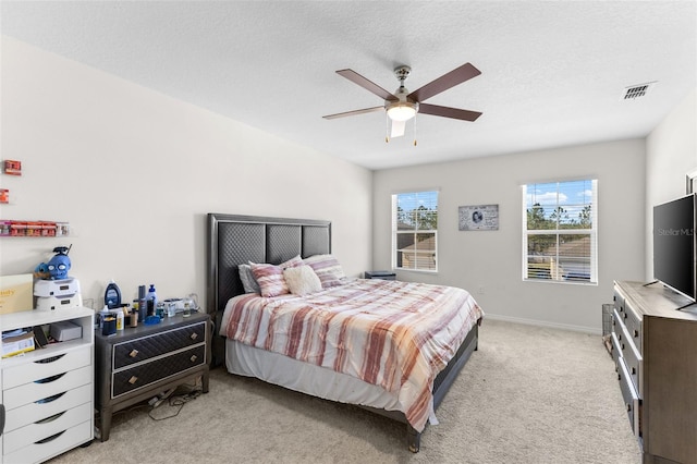 bedroom featuring ceiling fan, light colored carpet, and a textured ceiling