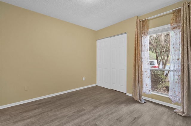 unfurnished bedroom with a textured ceiling, hardwood / wood-style flooring, and multiple windows