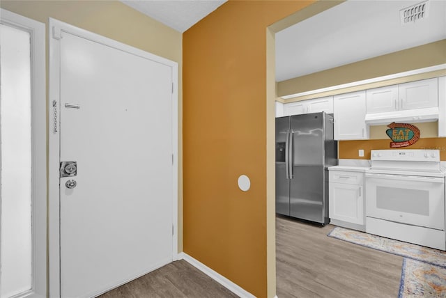 kitchen with light hardwood / wood-style floors, stainless steel fridge, white cabinets, and electric stove