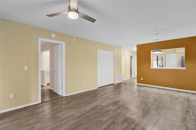 empty room featuring a textured ceiling, dark hardwood / wood-style floors, and ceiling fan