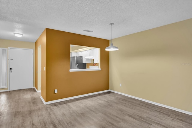 unfurnished dining area with wood-type flooring and a textured ceiling