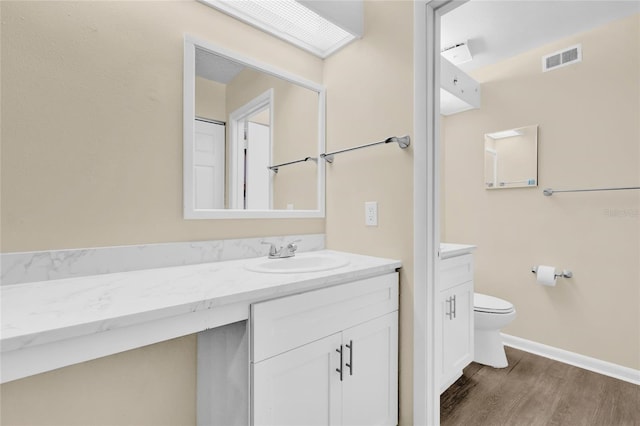 bathroom with hardwood / wood-style floors, vanity, and toilet