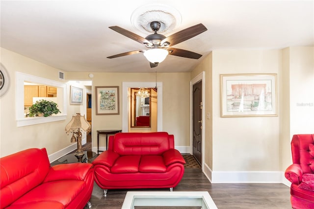 living room featuring ceiling fan with notable chandelier and dark wood-type flooring