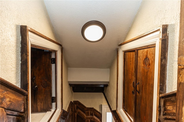 stairway with a textured ceiling and vaulted ceiling