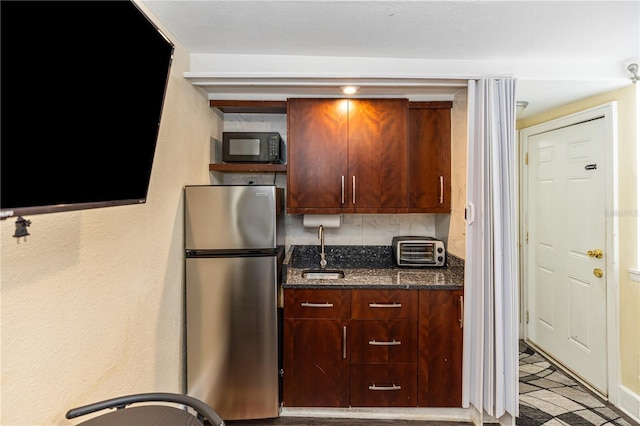 kitchen with tasteful backsplash, stainless steel fridge, sink, and dark stone counters