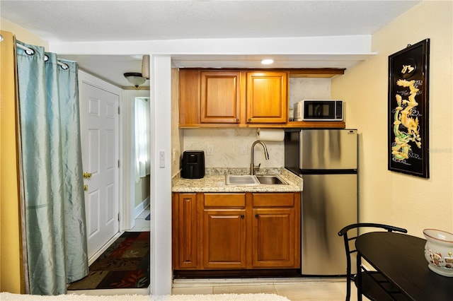 kitchen with backsplash, stainless steel fridge, light hardwood / wood-style floors, and sink