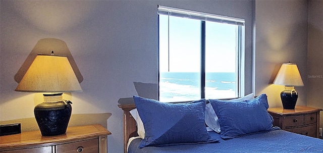 bedroom with a water view and multiple windows