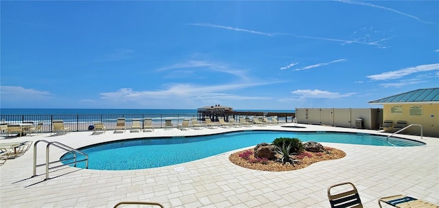 view of swimming pool with a patio area and a water view