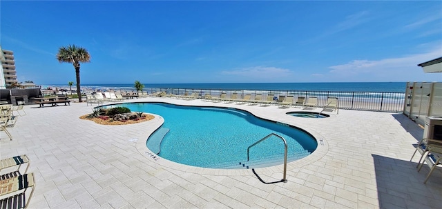 view of pool featuring a community hot tub, a water view, and a patio