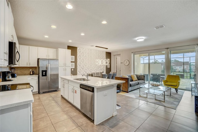 kitchen featuring white cabinets, sink, an island with sink, and appliances with stainless steel finishes