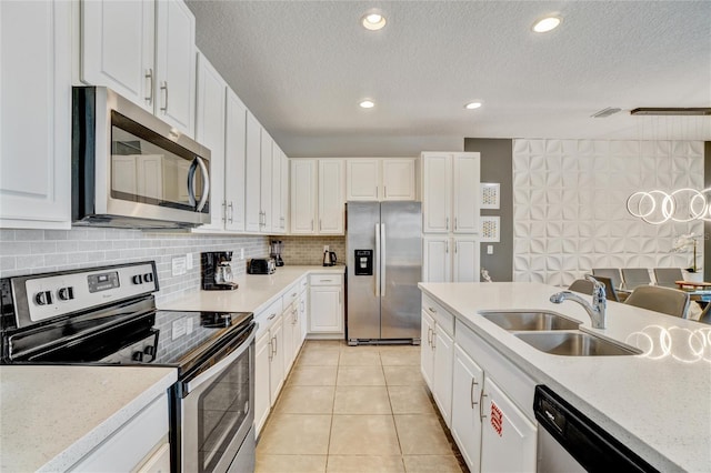 kitchen with sink, stainless steel appliances, light tile patterned floors, light stone counters, and white cabinets