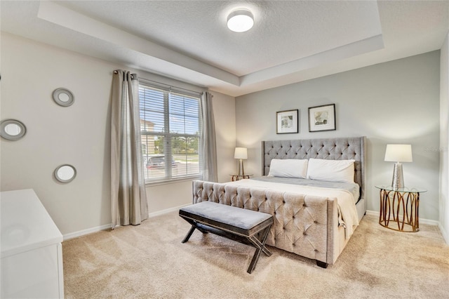 bedroom with light carpet and a tray ceiling