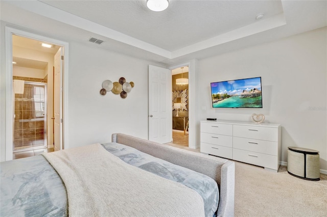 carpeted bedroom featuring a raised ceiling, a textured ceiling, and connected bathroom