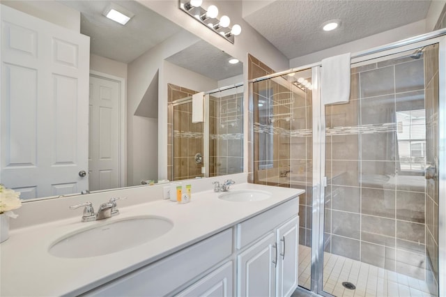 bathroom featuring vanity, a textured ceiling, and a shower with shower door