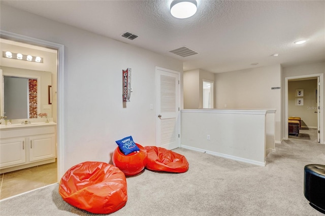 game room with light carpet, a textured ceiling, and sink