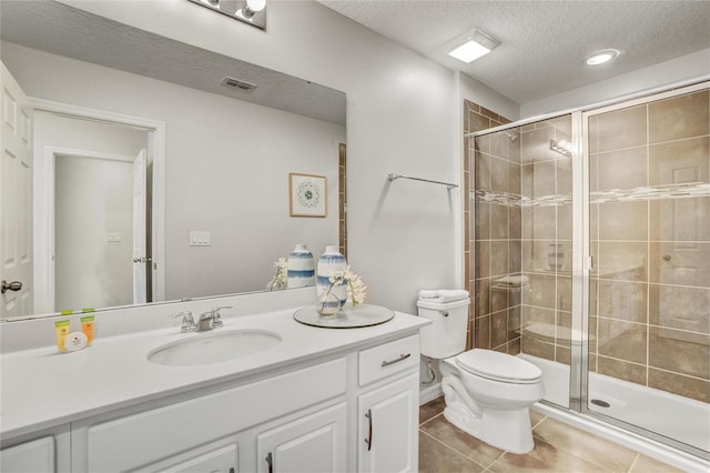 bathroom featuring vanity, a shower with door, tile patterned floors, toilet, and a textured ceiling