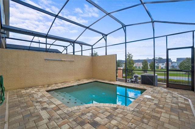 view of swimming pool with glass enclosure, cooling unit, and a patio