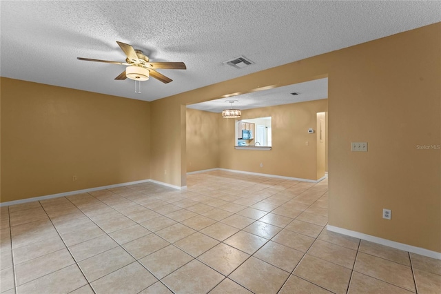 tiled spare room featuring ceiling fan with notable chandelier and a textured ceiling