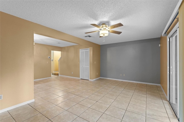 spare room featuring ceiling fan, light tile patterned floors, and a textured ceiling