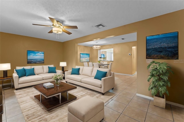 tiled living room featuring a textured ceiling and ceiling fan with notable chandelier